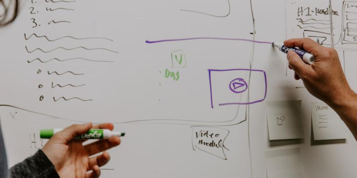 Two people collaborating by writing on a white board.