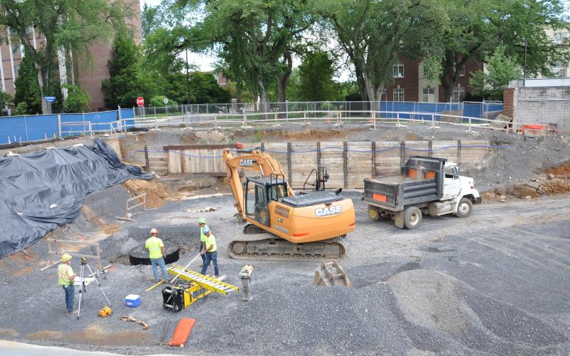 Workers are installing a special sanitary system; the protective timber shoring system supports the vertical sides of the excavation